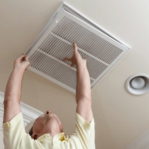 main opens air vent cover on ceiling to replace air filter for diy emergency air conditioning repair