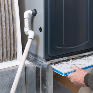 Man replacing dirty furnace filter in home furnace tune-up