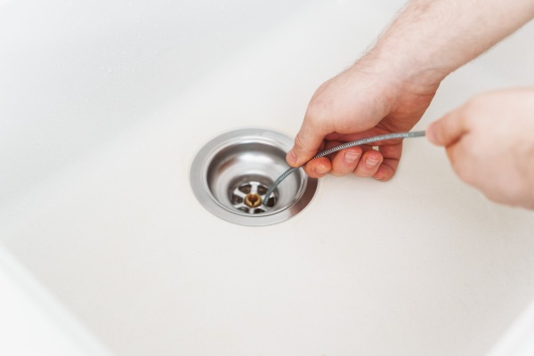 Plumber using drain snake to unclog kitchen sink