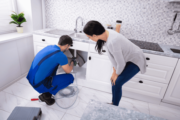 Plumber using drain snake to unclog kitchen sink