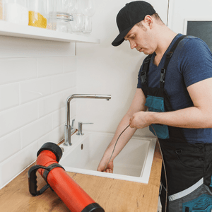 plumber snaking a kitchen sink