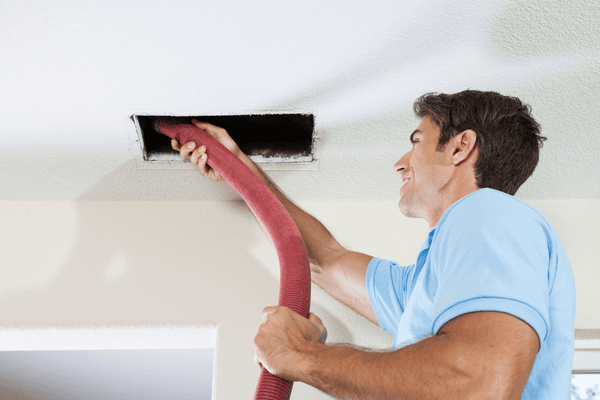 is air duct cleaning necessary- man with vacuum hose in uncovered vent