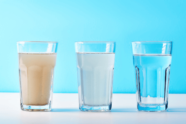 whole house water filter- Water filters. Concept of three glasses on a white blue background. Household filtration system.